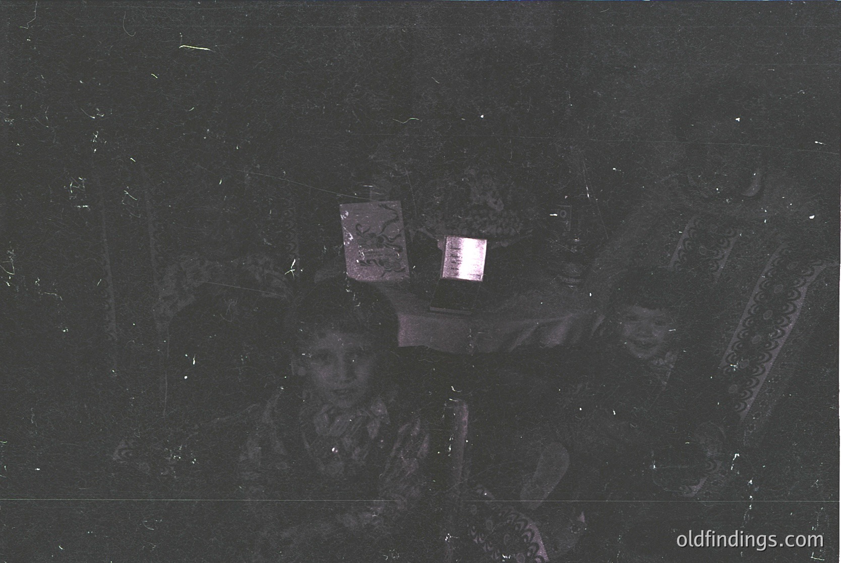 Vintage low-light portrait of two individuals in patterned headscarves, likely Eastern European or Middle Eastern. Blurred but distinct floral embroidery visible. Film grain and darkroom artifacts suggest 1970s–1980s era.