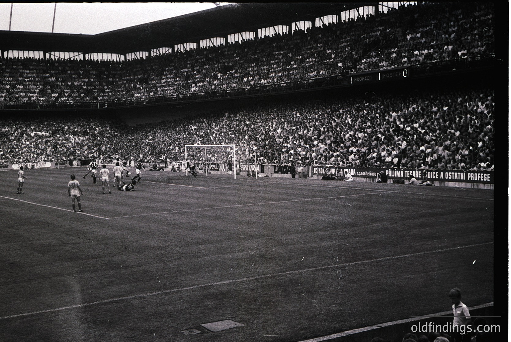 Vintage black-and-white stadium shot featuring a packed arena with players mid-match. Visible signage reads *"Palma Terme: Juice & Ostrich Professions."* Stadium seating and floodlights suggest a large-scale event, likely 1960s–1970s Italy.
