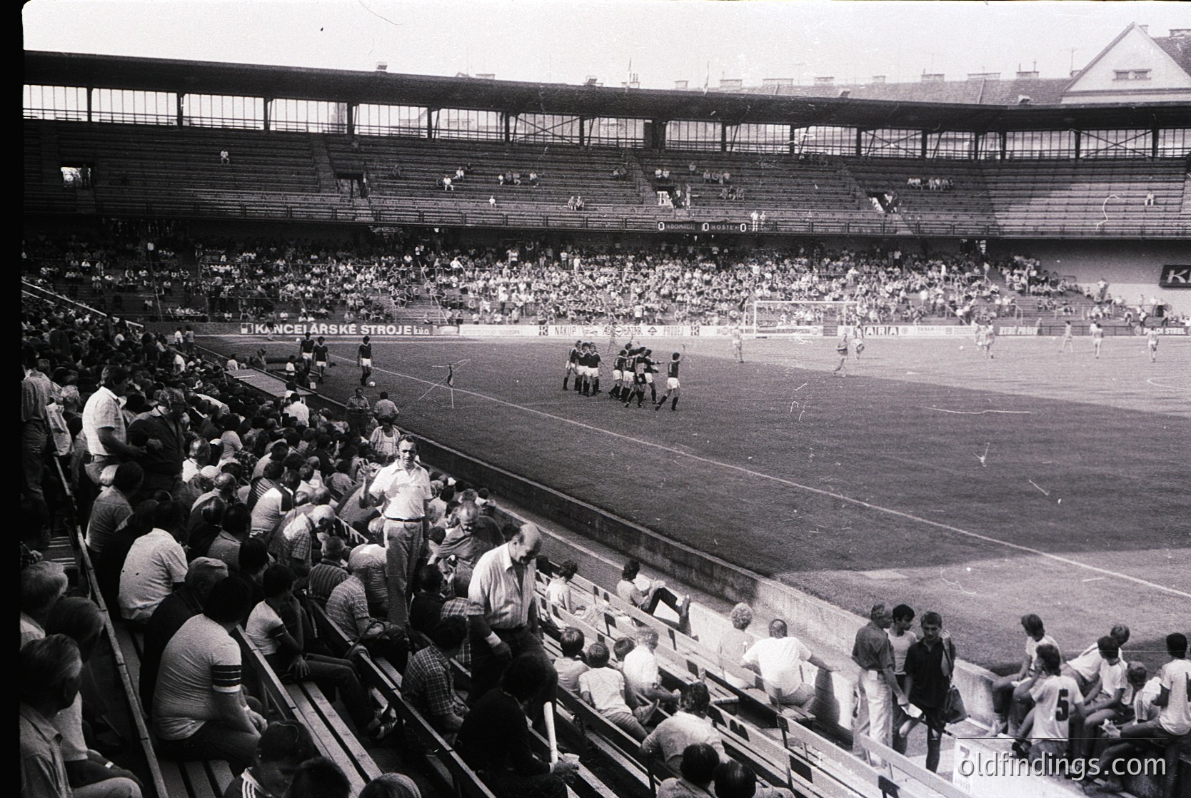 Vintage black-and-white photo of a packed stadium during a soccer match, featuring tiered seating and a large crowd. Players in action on the field, with spectators closely packed in stands. Signage in Cyrillic suggests Eastern European location, likely Bulgaria. Mid-20th century (1950s–1960s) atmosphere.