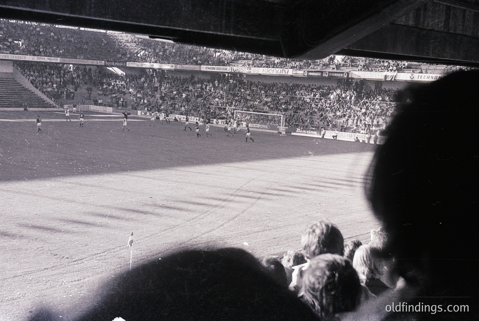 Black-and-white stadium shot showing packed stands with visible scoreboard reading "1-0" and "C.S. Steaua." Crowd fills tiered seating, with players and ball visible on field. Likely 1970s–1980s European football match.