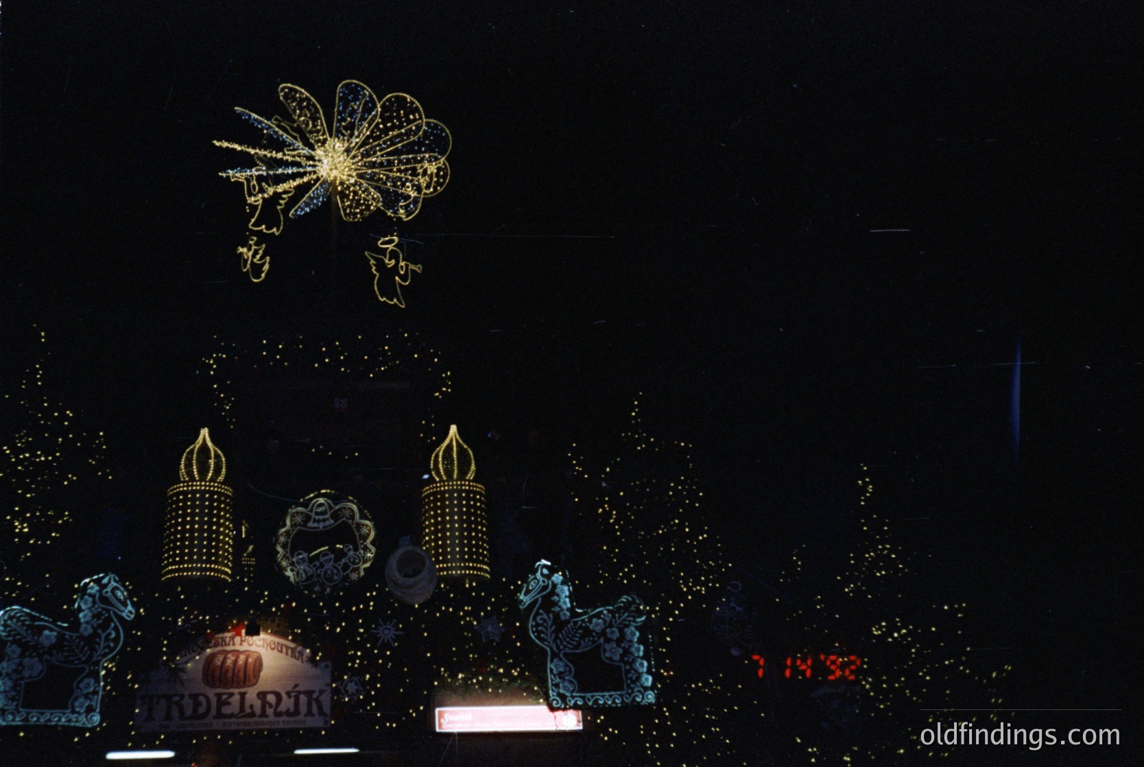 Vibrant nighttime fireworks display featuring intricate floral and dragon motifs. Illuminated Chinese characters "福" (blessing) and "2013" suggest a celebratory event, likely Lunar New Year. Decorative dragon statues flank a central platform, enhancing cultural symbolism. Urban setting with digital clock displaying 14:36.