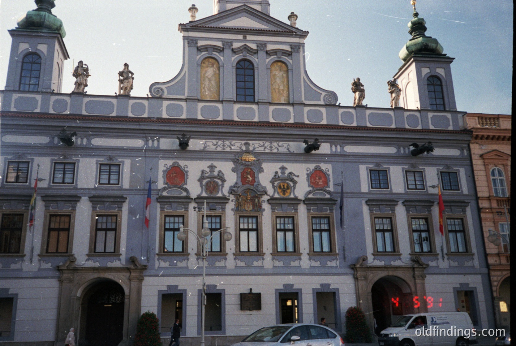 Baroque-style building with ornate façade featuring sculpted figures, heraldic crests, and decorative reliefs. Symmetrical design with two towers, arched entrance, and large windows. Likely a historic European civic or governmental structure.