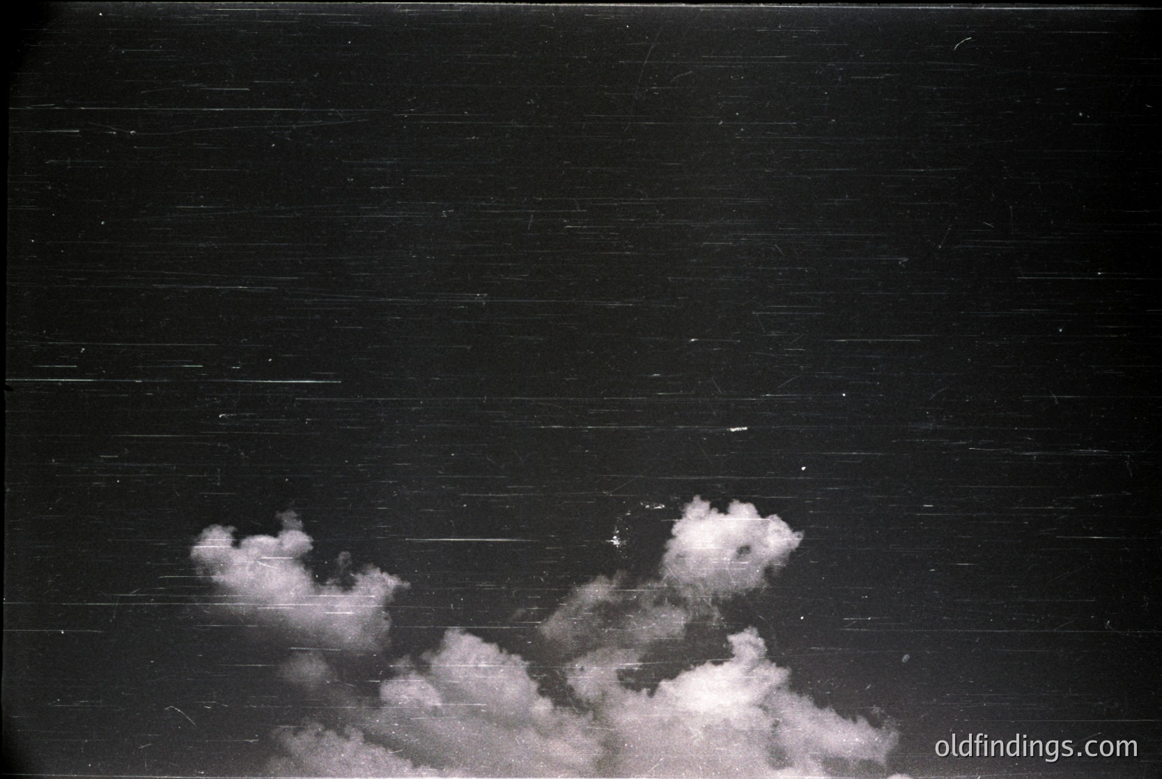 High-contrast black-and-white shot of dramatic cumulus clouds against a dark sky, framed by horizontal wooden planks. Likely mid-20th century due to grain and composition. Ideal for moody atmospheric or vintage-inspired design projects.