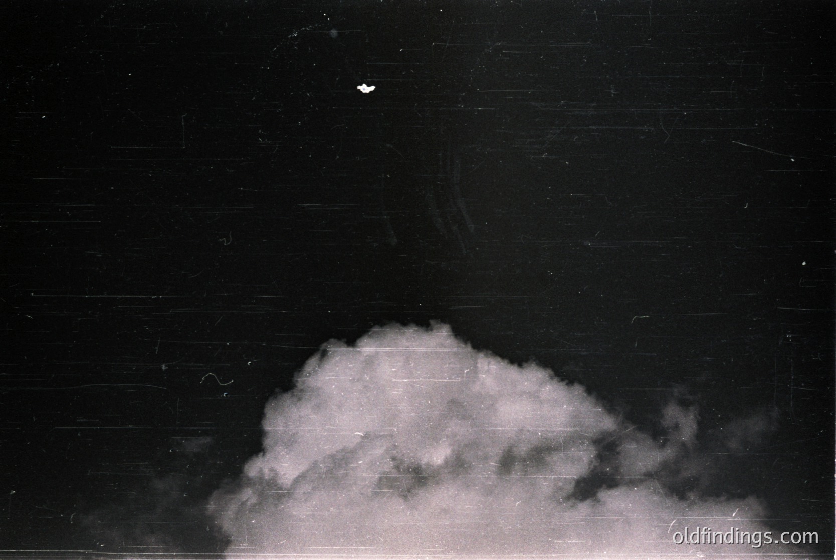 Vintage black-and-white photo of a lone bird silhouetted against a dense, low-hanging cloud formation. The composition emphasizes atmospheric texture and contrast. Likely mid-20th century, possibly for industrial or documentary use.