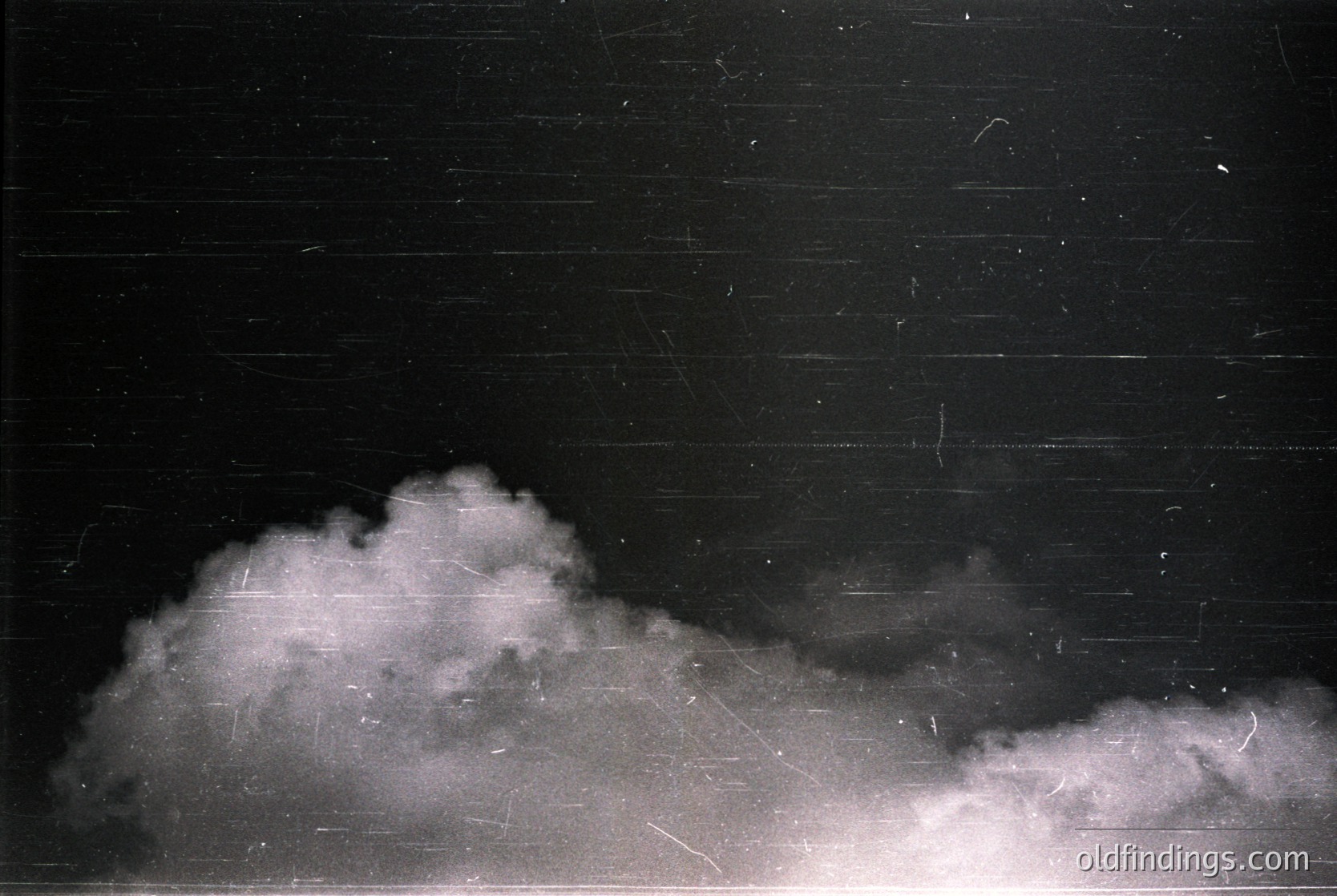 Vintage black-and-white photo of dense, low-hanging clouds against a dark sky, likely captured with early film grain. The texture suggests mid-20th century photography (). Ideal for moody, atmospheric stock imagery or historical film references.