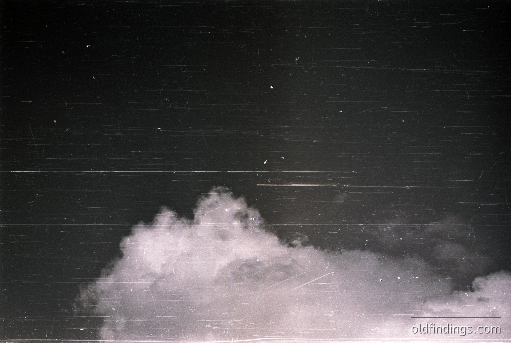 Vintage black-and-white photo of dense fog obscuring a horizontal wooden structure, likely a fence or wall. Streaks suggest motion blur from camera or wind. Atmospheric, moody composition ideal for abstract or nature-inspired visuals.