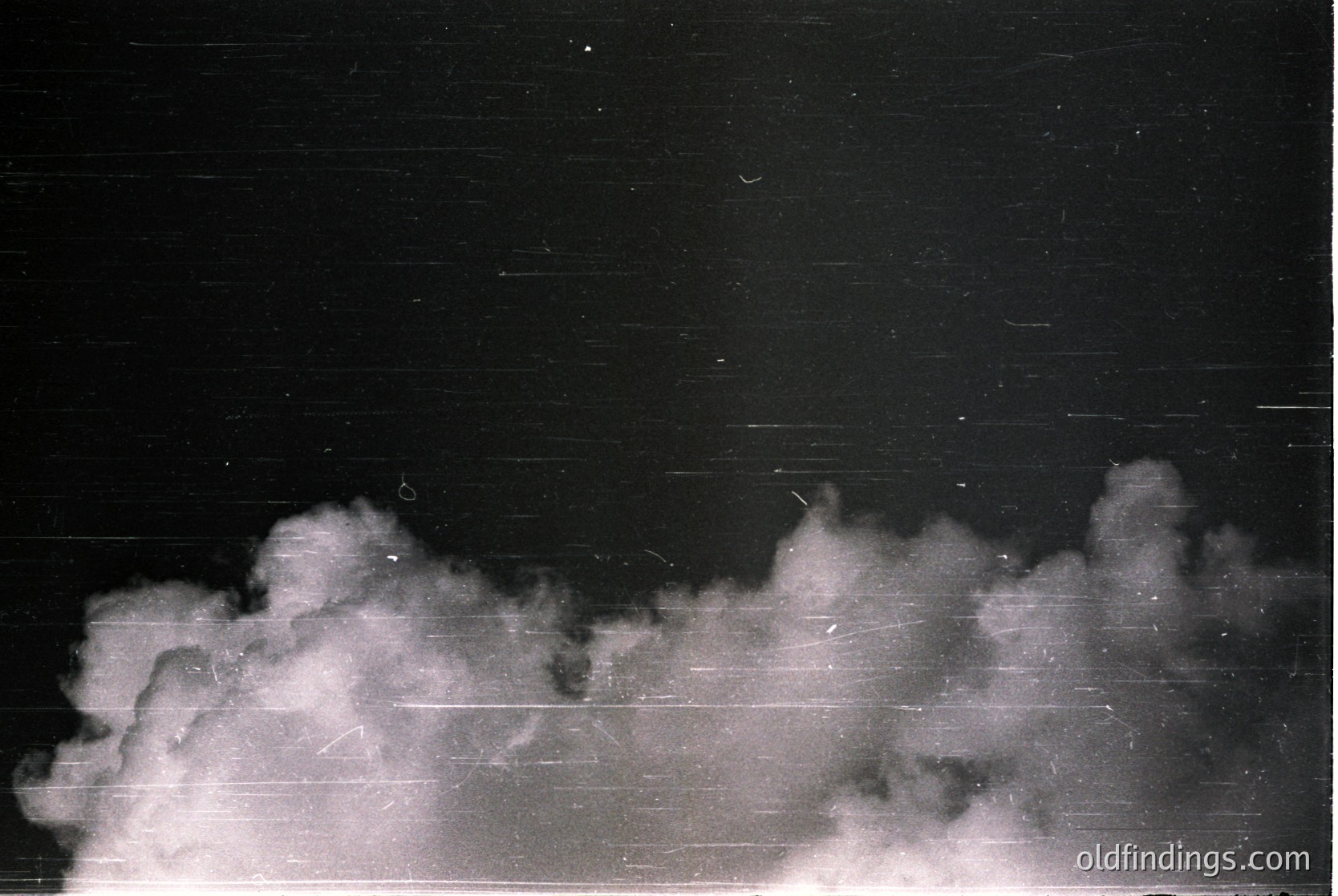 Black-and-white industrial smoke plume rising against a night sky, likely from a factory or chimney stack. Horizontal streaks suggest long-exposure photography.