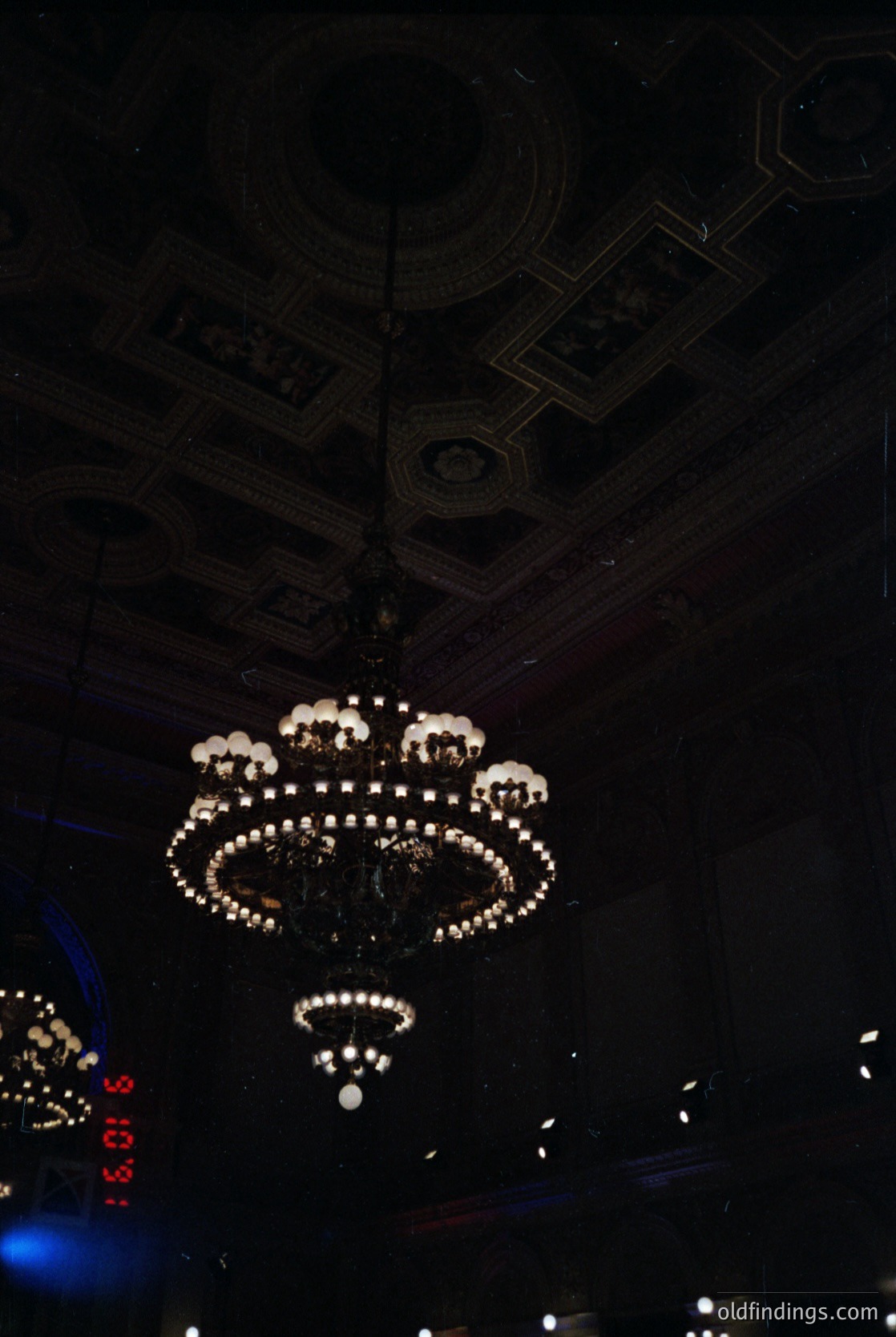 Art deco chandelier with geometric ceiling patterns, likely from a 1920s–1940s European café or theater. Intricate crystal details and symmetrical design evoke mid-century elegance. Perfect for vintage-inspired interiors or historical research. éInteriors