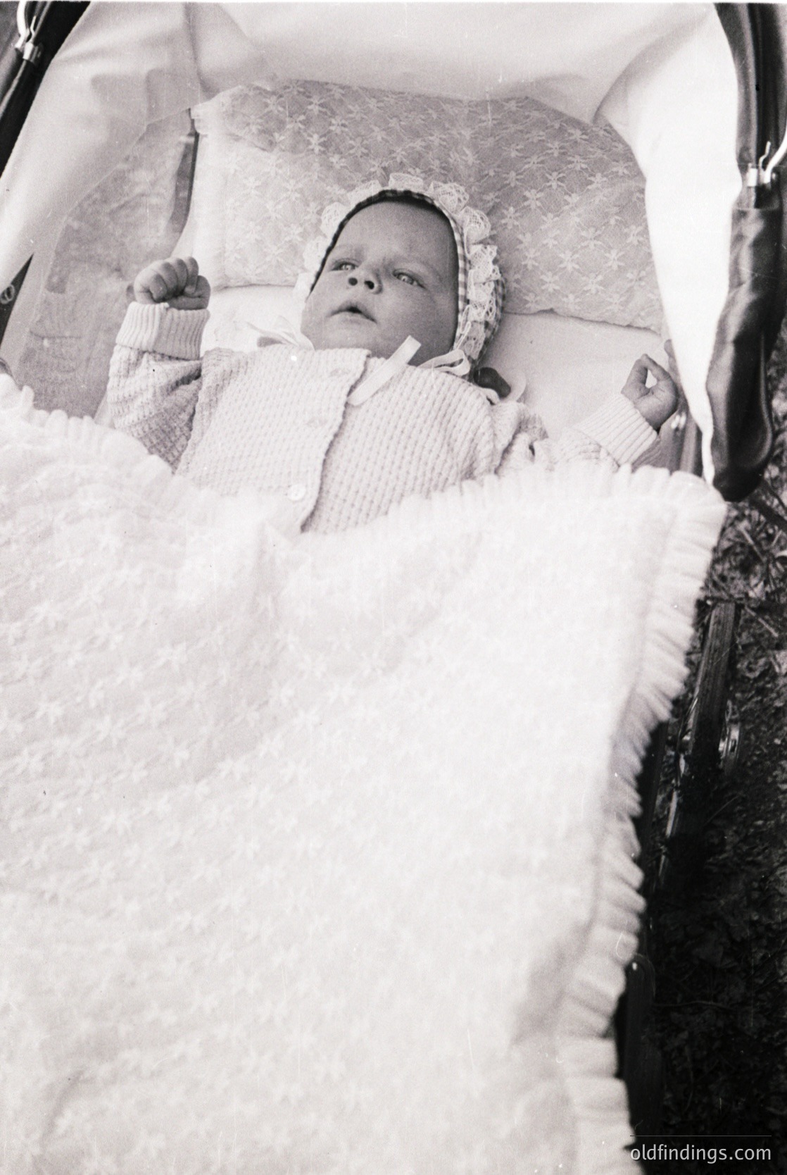 Classic 1960s–70s baby buggy with plush white fur lining, showcasing vintage infant comfort design. Infant wrapped in knitted blanket, seated in a cushioned, padded seat. Warm, nostalgic aesthetic evokes mid-century parenting culture.