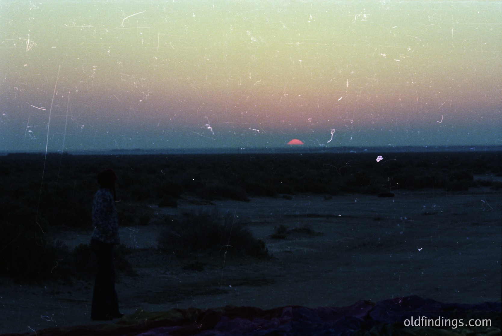 Vintage photograph of a seaside sunset through cracked glass, revealing muted blues and pinks. Distorted reflections create abstract patterns. Likely mid-20th century, possibly . Evokes nostalgia for analog photography and coastal landscapes.