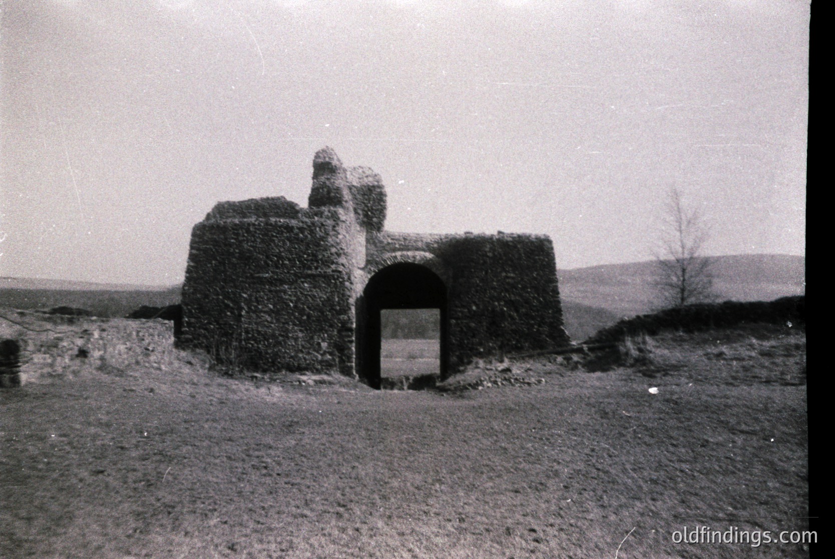 Stone watchtower with arched entrance, likely a historic lookout or defensive structure. Constructed from rough-hewn blocks, showing signs of age and weathering. Open landscape with sparse vegetation in background. Black-and-white, suggesting mid-20th century or earlier.