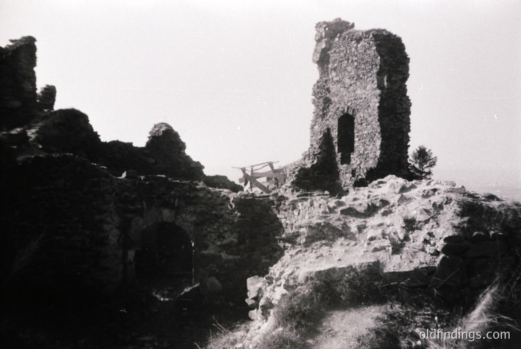 Ruins of a medieval stone tower perched on rocky terrain, featuring a single arched doorway and crumbling walls. Black-and-white photograph captures weathered textures and minimal vegetation. Likely Eastern European, 19th–early 20th century.