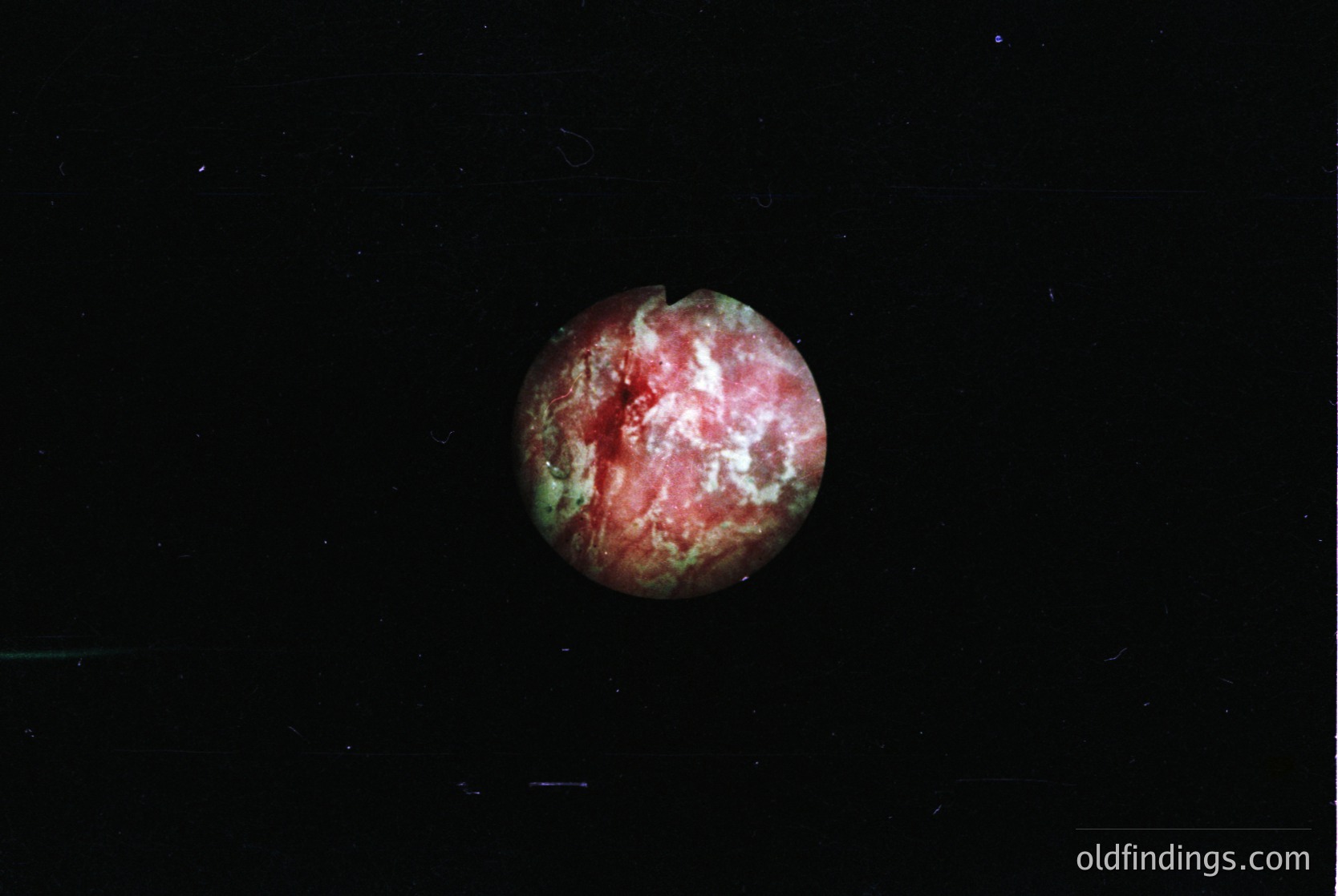 Close-up of a single, irregularly textured gemstone—likely a **pink tourmaline**—set against a black background. The stone exhibits zoning with pink and greenish hues, indicative of natural color variation. Ideal for jewelry design, mineral studies, or gemological reference.