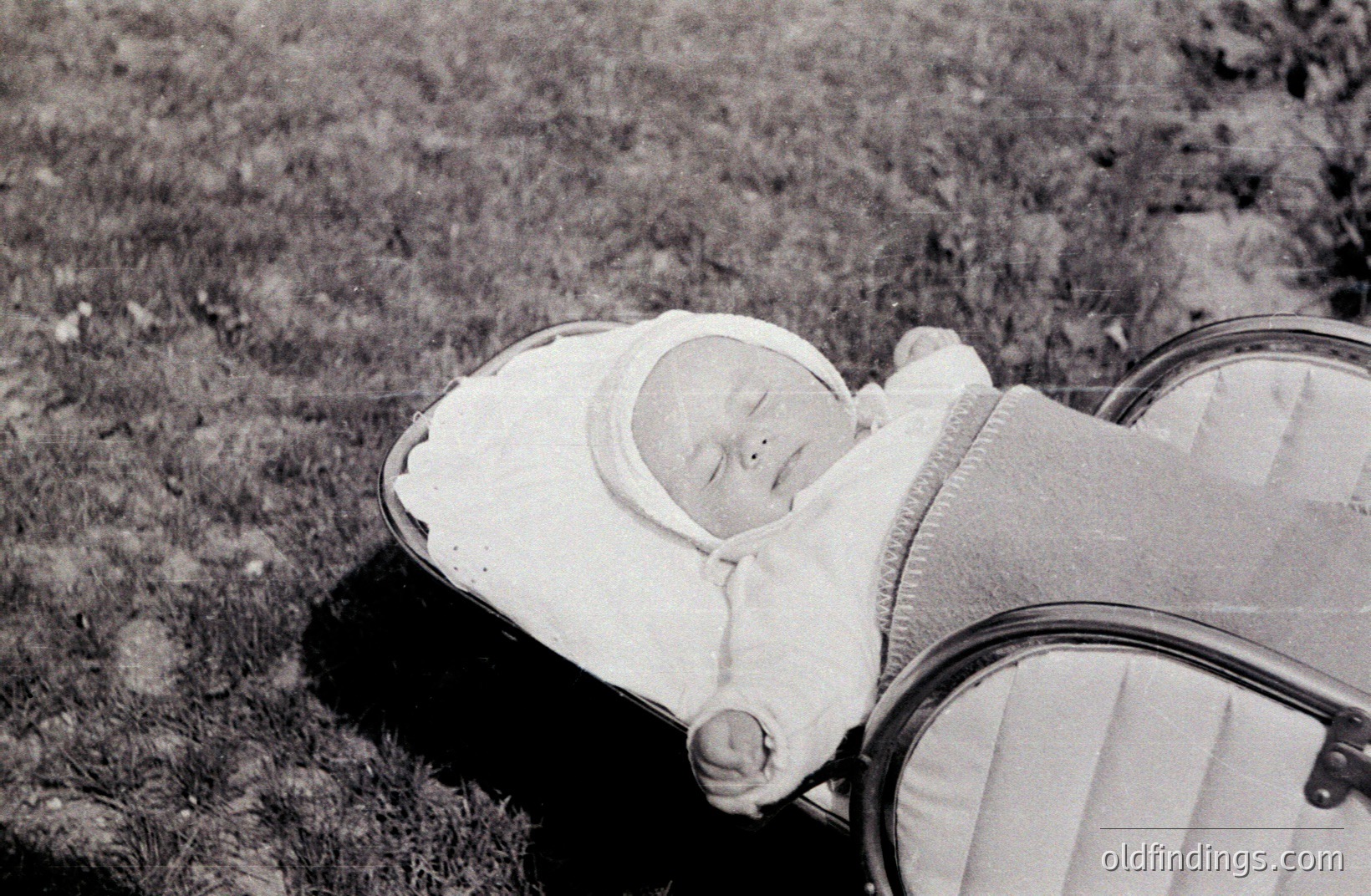 Infant lies peacefully in a vintage pram with striped lining. The baby wears a traditional white bonnet. Likely 1950s or 1960s, demonstrating a nostalgic family moment. Image showcases classic design elements. Suitable for vintage aesthetic projects.