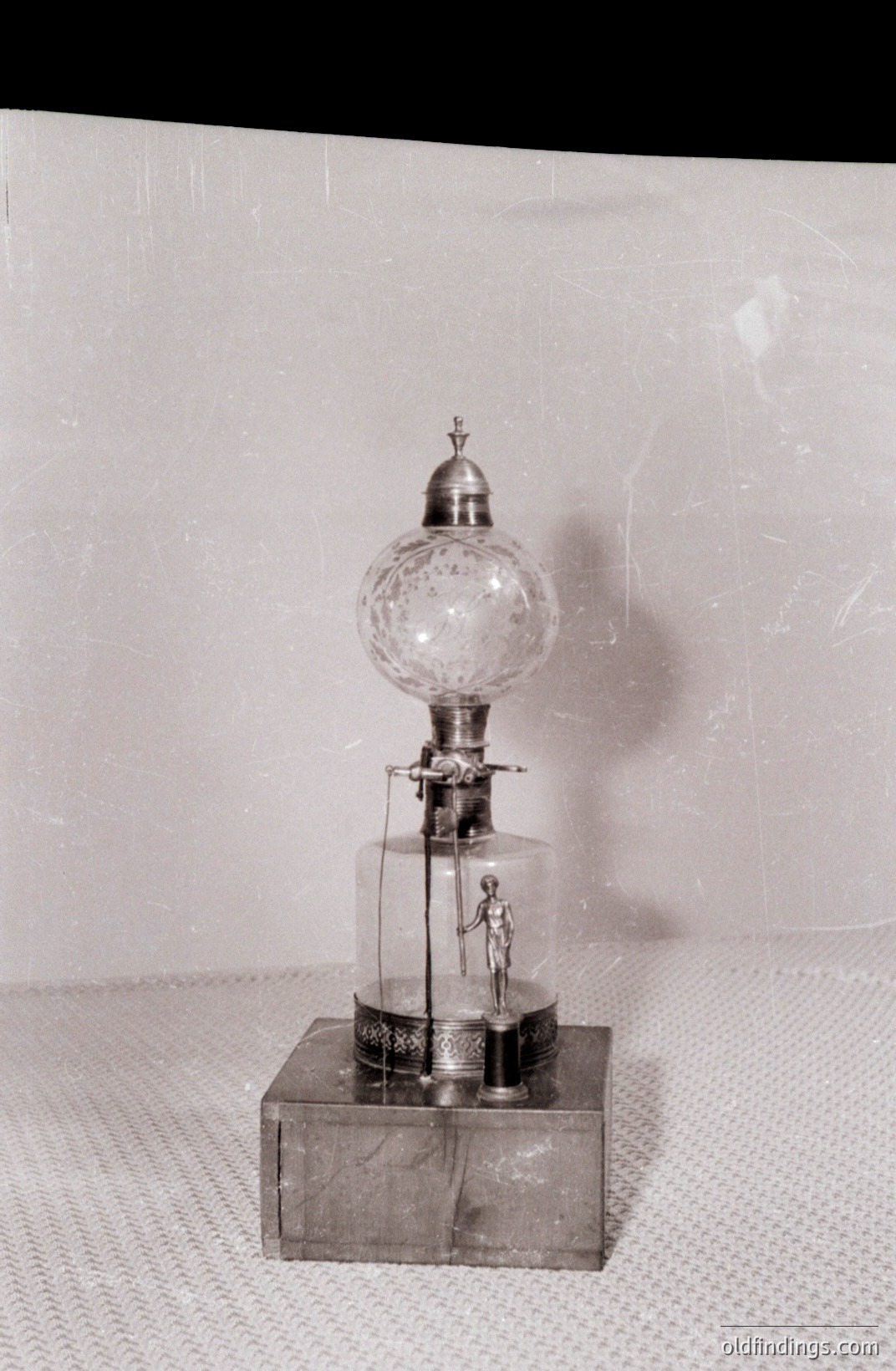 Intricate automaton depicting a miniature figure operating a bellows within a glass dome. Detailed mechanical display rests on an ornate base, showcasing a complex interplay of motion and craftsmanship. Likely a novelty item from the late 19th or early 20th century. A collector's item for antique enthusiasts.