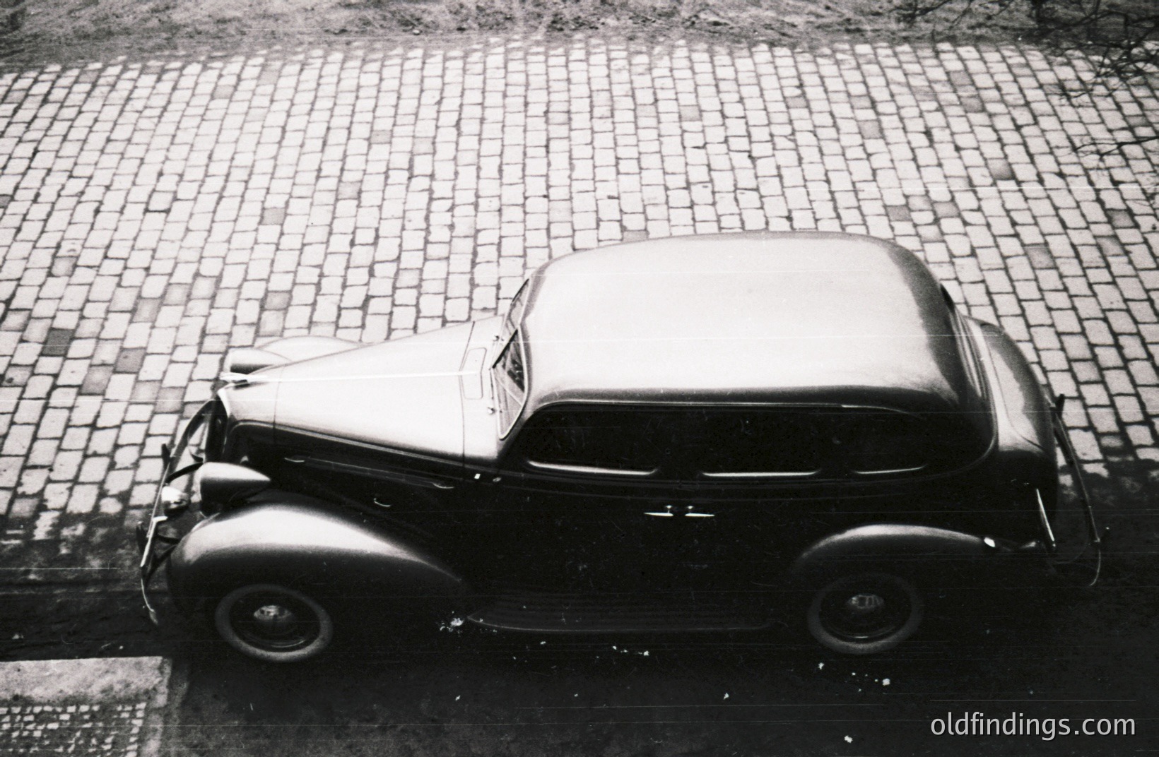 High-angle view of a classic 1937-1939 LaSalle sedan, showcasing its streamlined Art Deco design. Parked on a cobblestone street. The car's long hood and rear fender curves are distinctive. A valuable example of 1930s automotive styling.