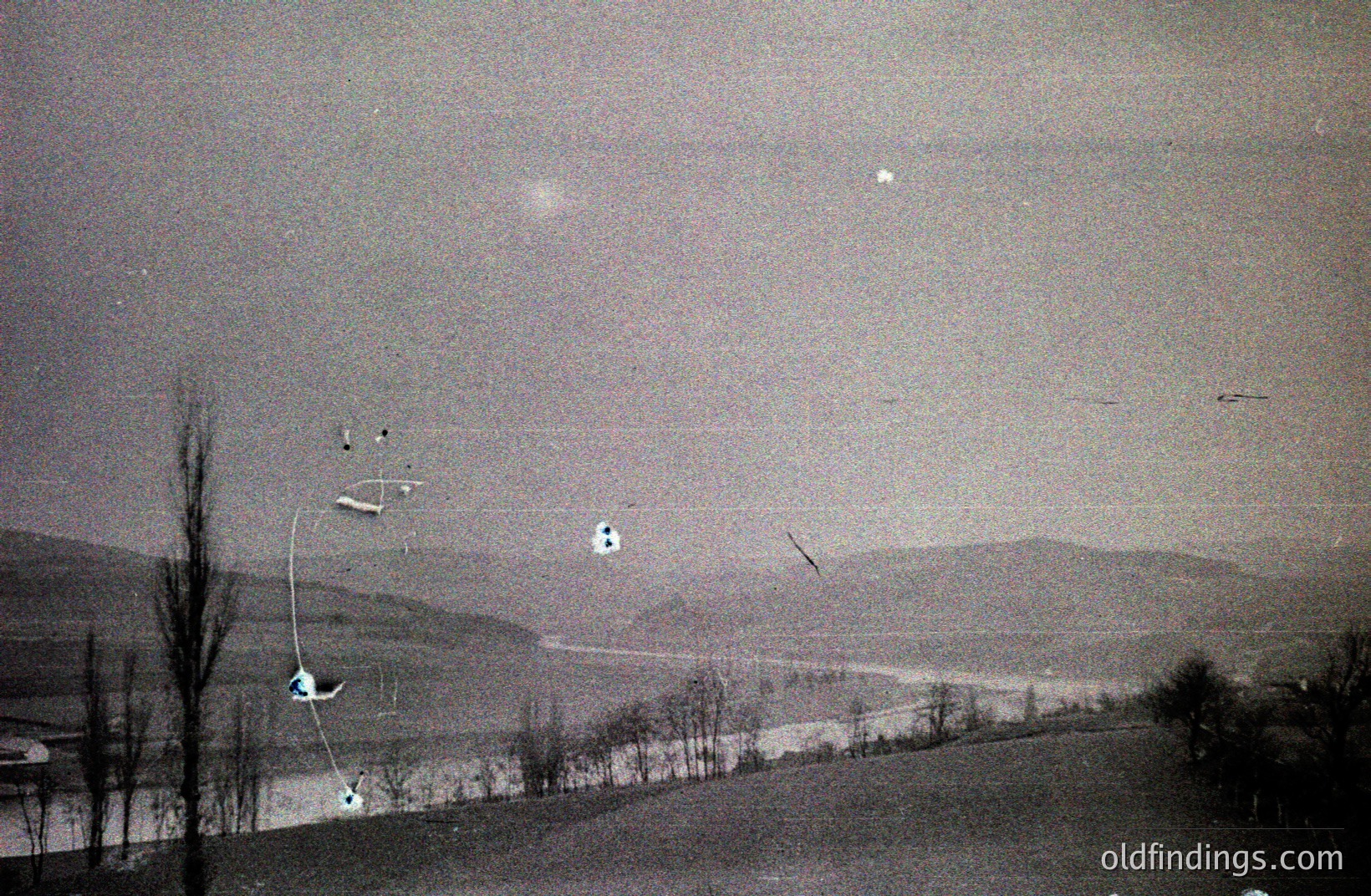 Striking aerial view captures skiers navigating a snow-covered landscape with distant, hazy mountains. Likely a promotional image for a ski resort, possibly in the 1960s or 70s. The image quality suggests a vintage print.