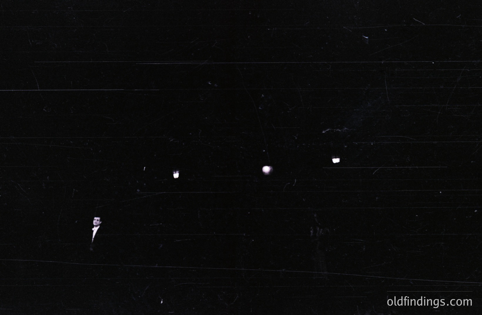 Image depicts a black surface with multiple prominent light leaks and dust spots scattered across the frame. The texture suggests aged photographic film or paper. Suitable for backgrounds or textural overlays in design projects. Likely a scanned vintage print.