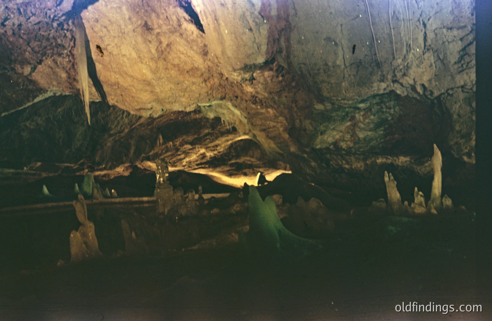 Interior of a cave, showcasing rock formations and illuminated by artificial lighting. A dark path leads deeper into the cavern. Likely a tourist attraction. Appears to be a limestone cave, possibly in Eastern Europe.