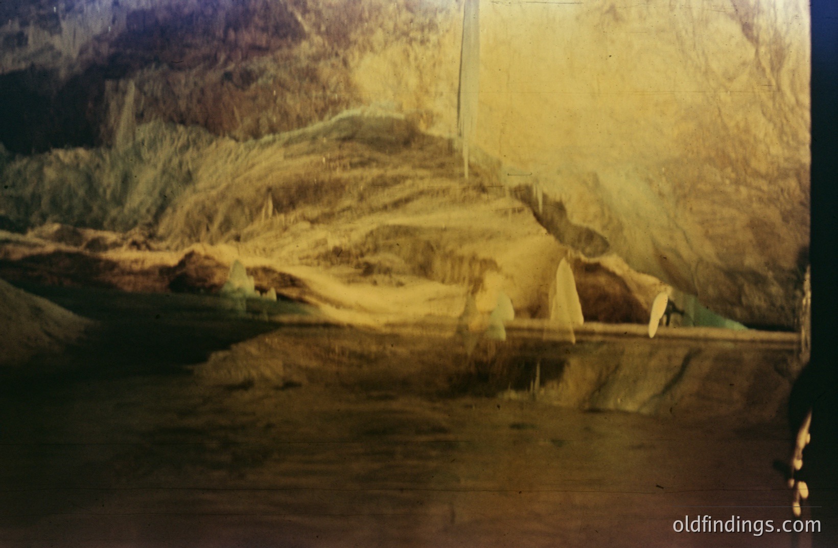 A diorama depicting an alpine landscape, likely within a museum or educational setting. The scene features a painted backdrop of mountains and a miniature, constructed foreground with artificial rock formations and sparse greenery. A slightly faded, yellowish color cast indicates age.