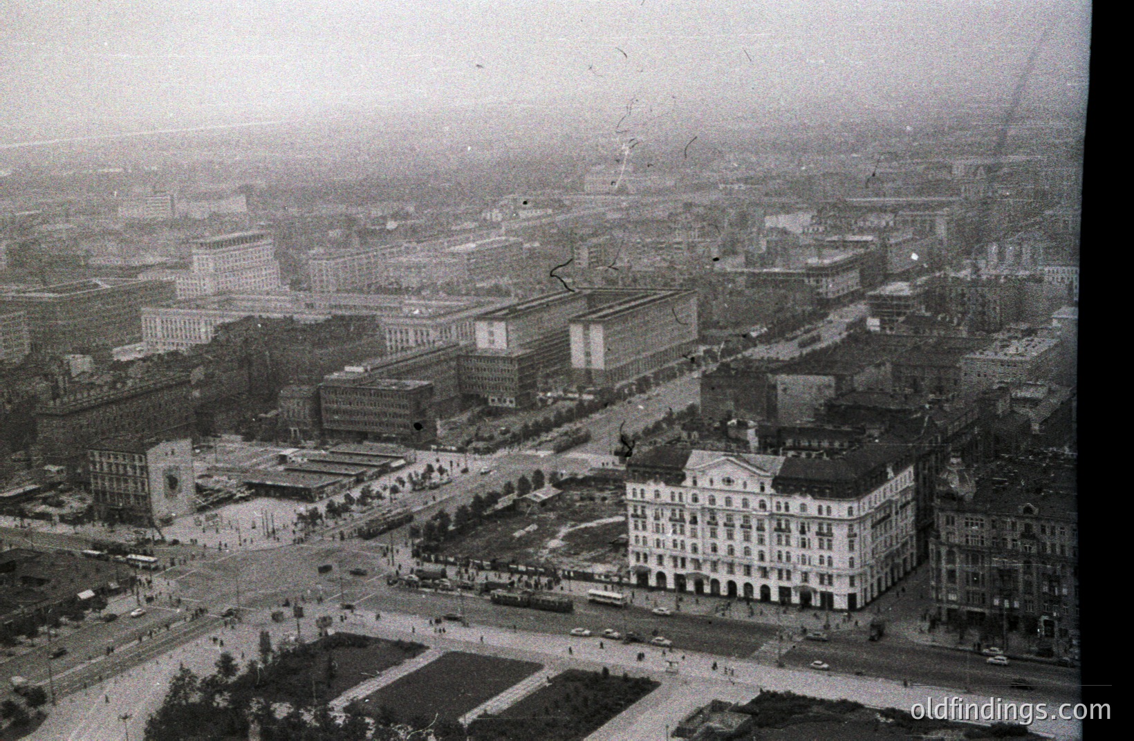 High-angle view of Varna, Bulgaria, showcasing a blend of architectural styles. The imposing, modernist Palace of Culture and Sport dominates the scene, contrasted by older, ornate buildings nearby. Appears to be mid-20th century, likely 1960s-1970s. City planning evident.