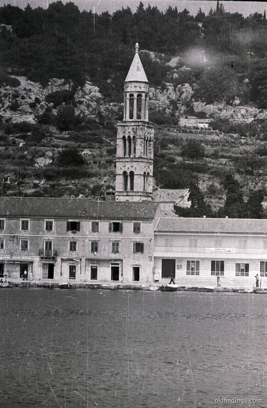 A multi-story building with a prominent bell tower dominates the coastal scene. The architecture features arched windows, balconies, and a tiled roof, set against a backdrop of dense, forested hillside. Likely Black Sea coastal town, early-mid 20th century. Commercial/architectural reference potential.