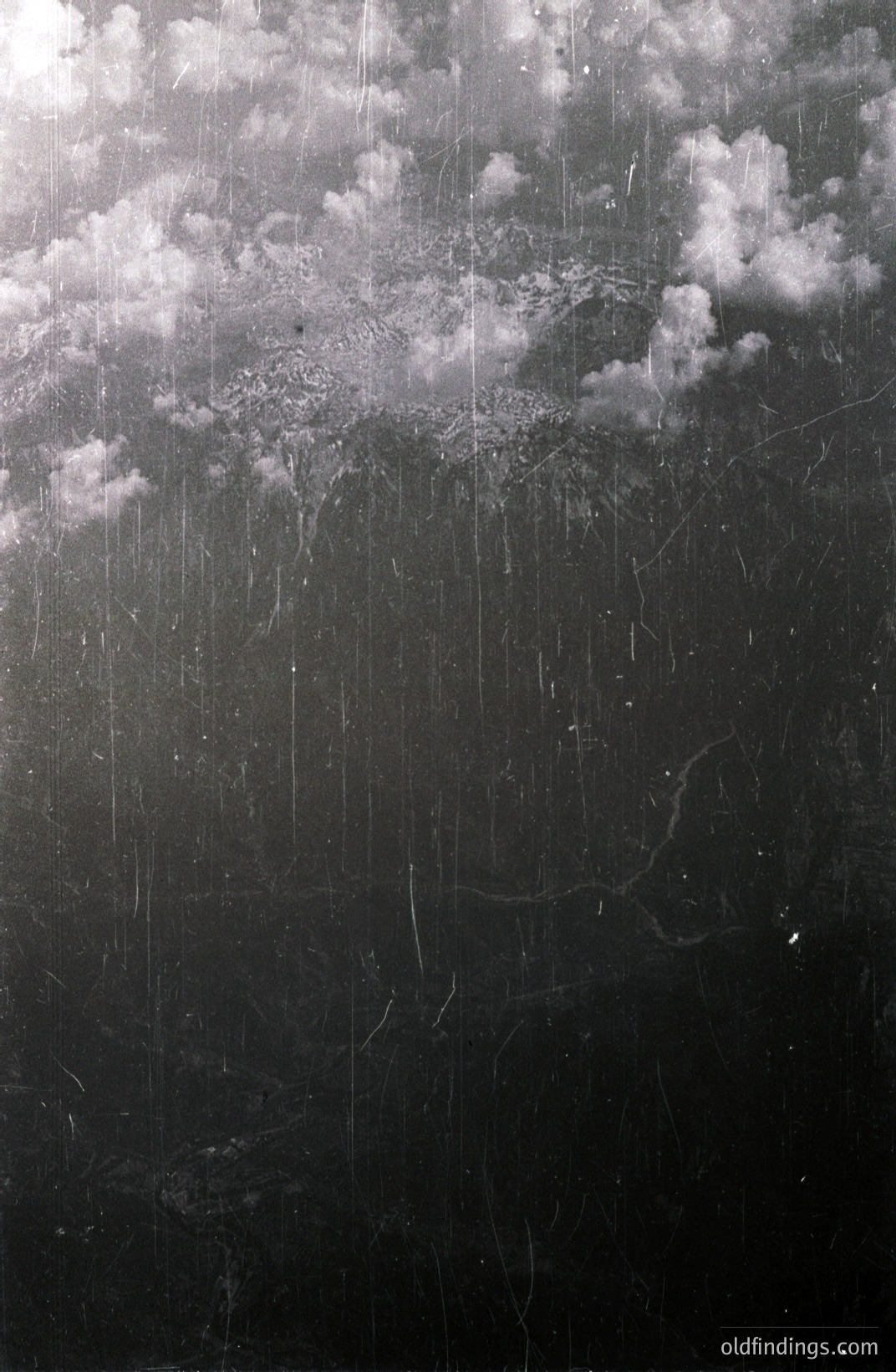 Striking, high-contrast monochrome print. Shows a sky with substantial cloud cover, heavily textured with visible dust and scratches on the photographic emulsion. Likely an early or vintage print exhibiting age-related deterioration. Strong visual appeal for design or historical study.