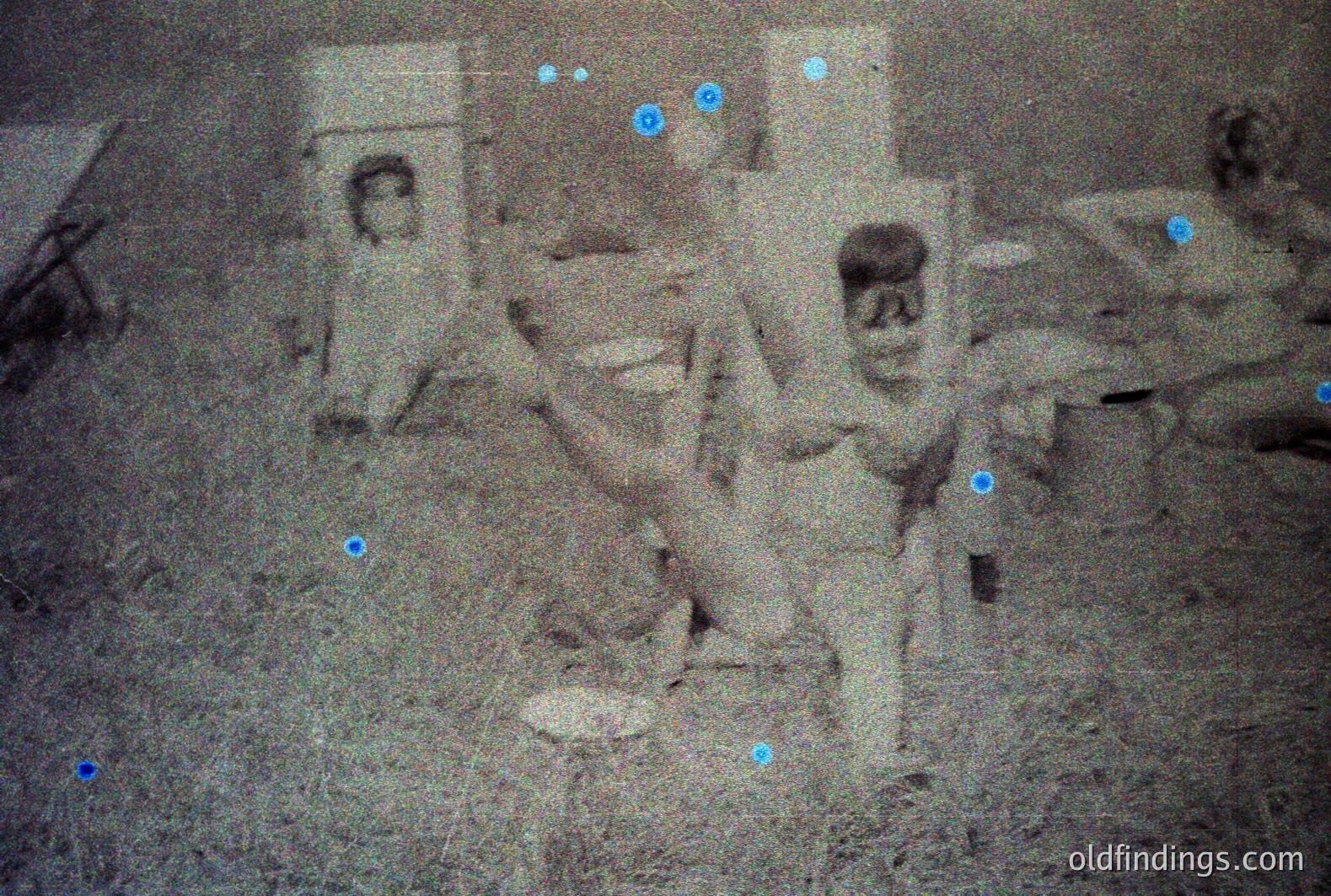 A faded, grainy photograph shows three children in what appears to be a rural or overgrown outdoor setting. One child stands between two others, all in what looks like rough-spun, loosely-fitted clothing. The scene is bathed in shadow, obscuring details, with visible foliage and indistinct background elements. Likely 1930s-1950s.