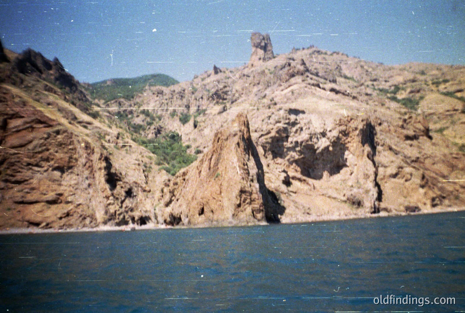 Striking sandstone cliffs rise dramatically from the dark blue sea. This appears to be the Albena cliffs near Varna, Bulgaria. Eroded formations and sparse vegetation define the landscape. Likely taken in the 1970s or 80s given the film quality. A classic seaside panorama.