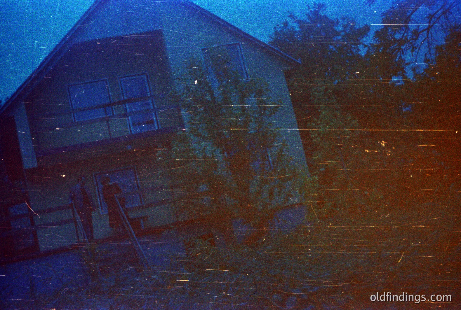 A two-story house with a gabled roof is partially obscured by foliage. Strong vertical color shifts, likely from dye fading, dominate the image. Architectural style suggests mid-century modern. Visible wear/scratches indicate age and potential stock photo/archival use. 1970s era film. -fade