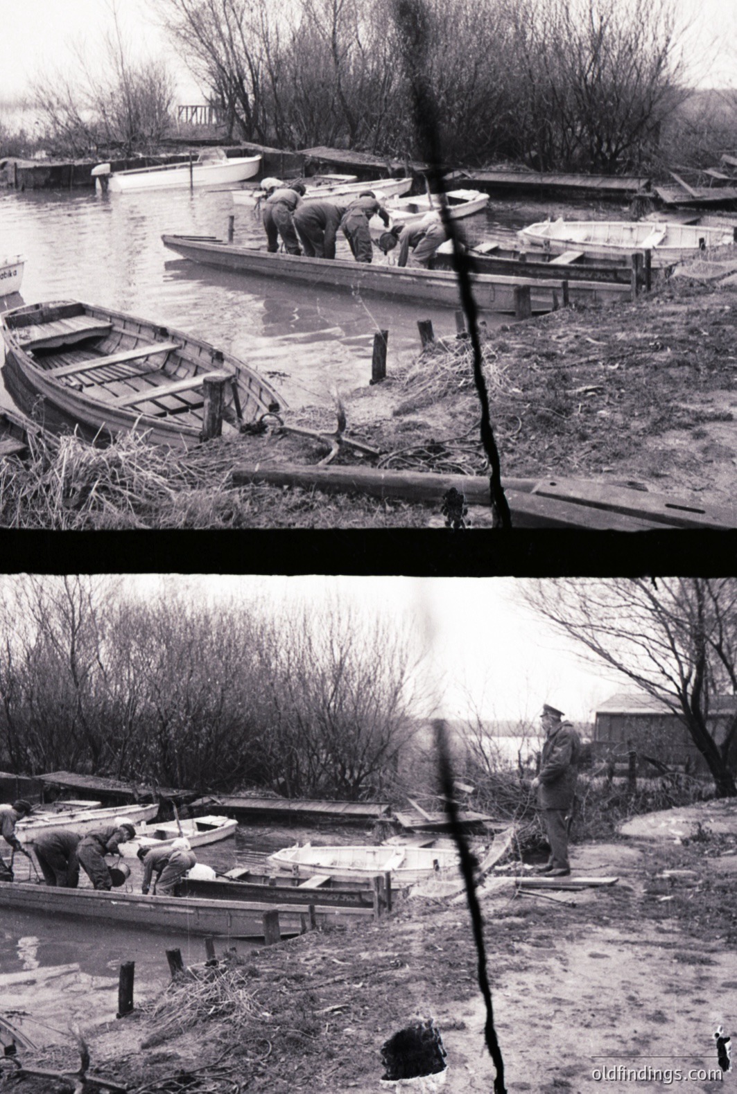 Several men are observed working on boats in a flooded area. A damaged rowboat is prominent near the foreground while several other hulls rest on the water and muddy ground. A man in uniform stands observing, likely supervising the repair. Appears to be post-war recovery work.