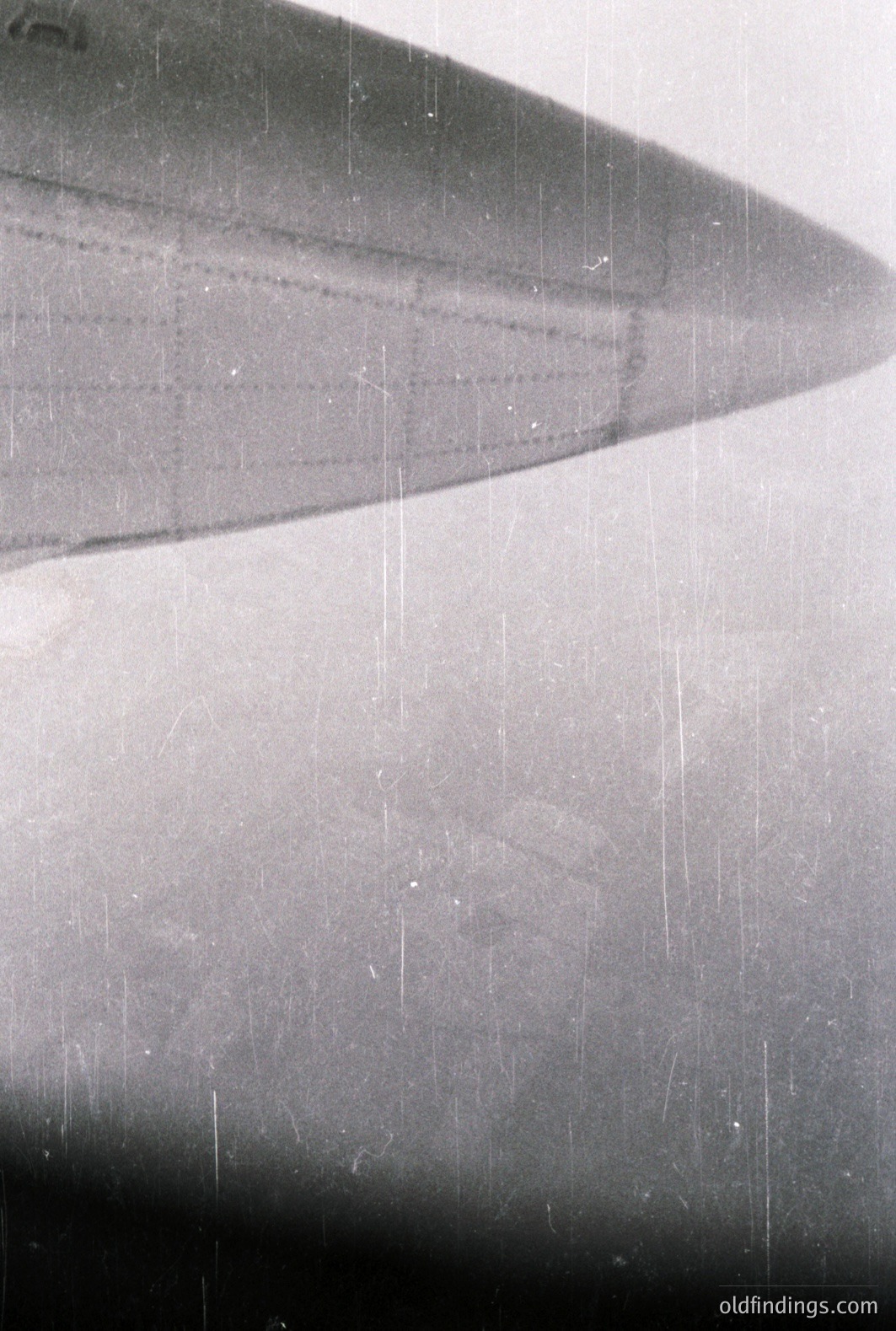 Close-up image reveals a blurred, slightly distressed surface. Possible architectural detail—perhaps a curved wall—is suggested by the receding lines and shadows. Extensive scratches and dust speckle the surface, indicative of age and possible archival origin. Likely a photographic negative.