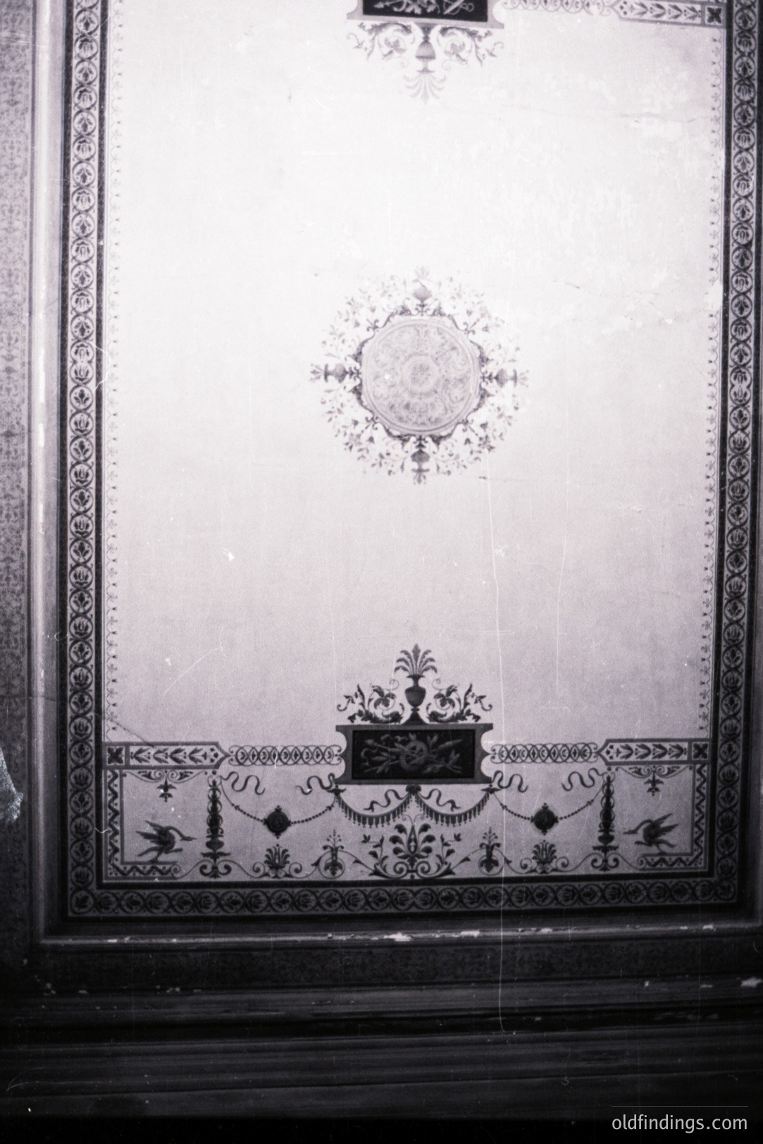 Ornate black & white wall panel featuring a central floral motif, decorative scrollwork, and a symmetrical border. Likely from a stately home, possibly late 19th/early 20th century. Suggests architectural detail, design reference. High commercial value for restoration or pattern inspiration.