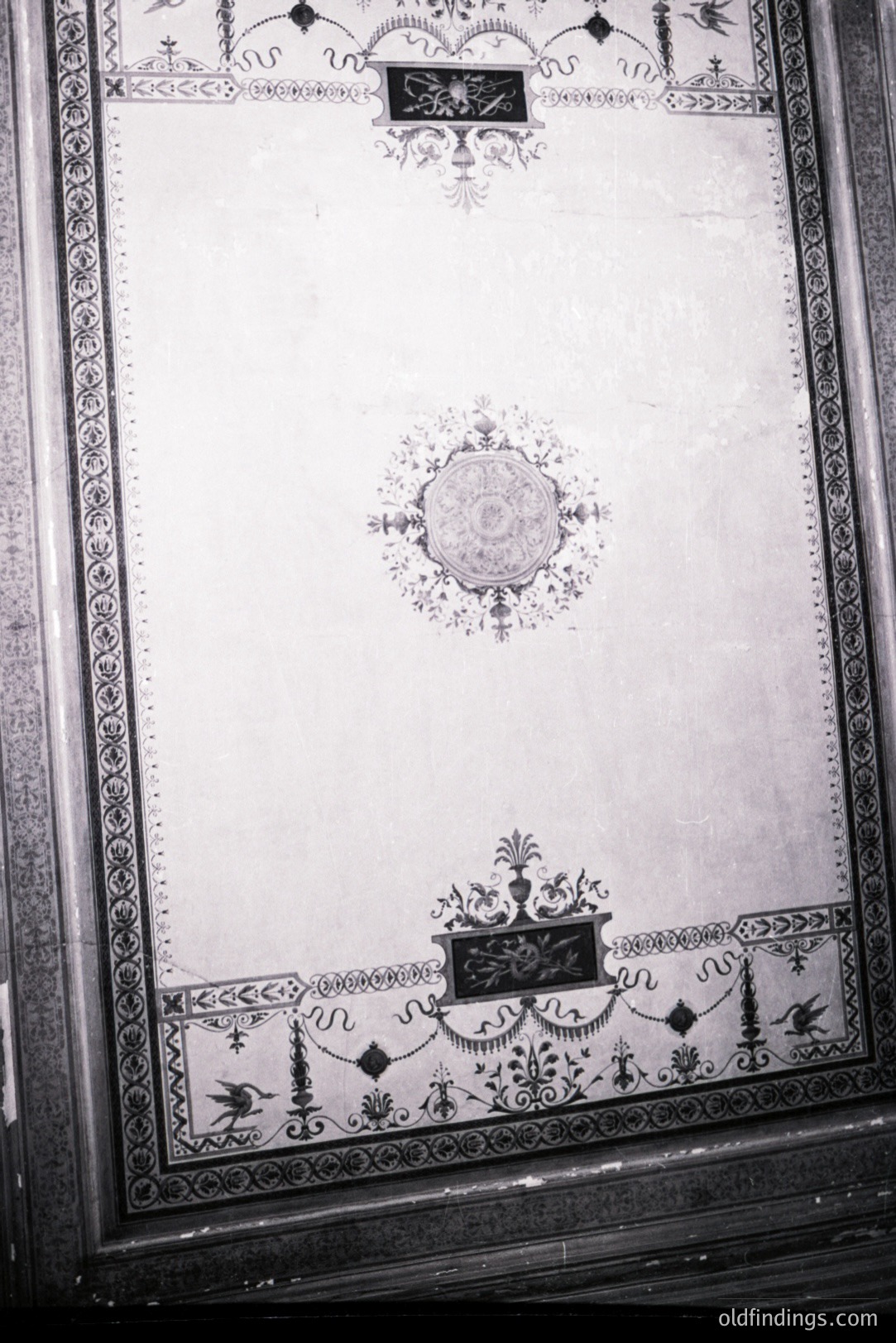 Highly ornamental plasterwork ceiling detail, likely from a historic European building. Intricate floral motifs, scrollwork, and a central rosette adorn the surface. Appears to be black and white photography, potentially a documentation of architectural heritage.