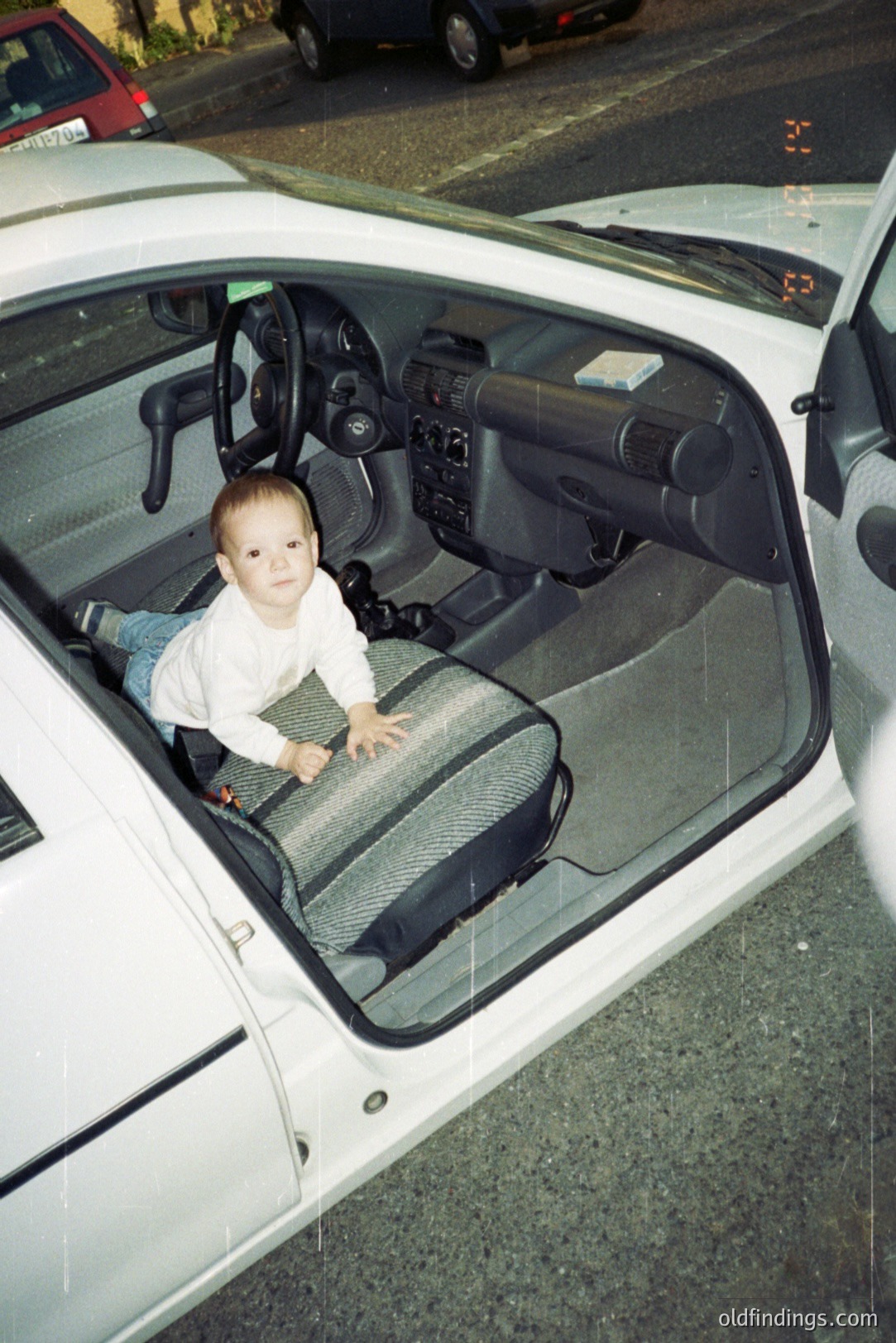 Young boy seated in a white Chevrolet Blazer interior. Photograph captures a casual, candid moment. The vehicle appears well-maintained, suggesting a popular model from the 1990s. Likely a family snapshot, offering insight into domestic life and automotive design of the era.