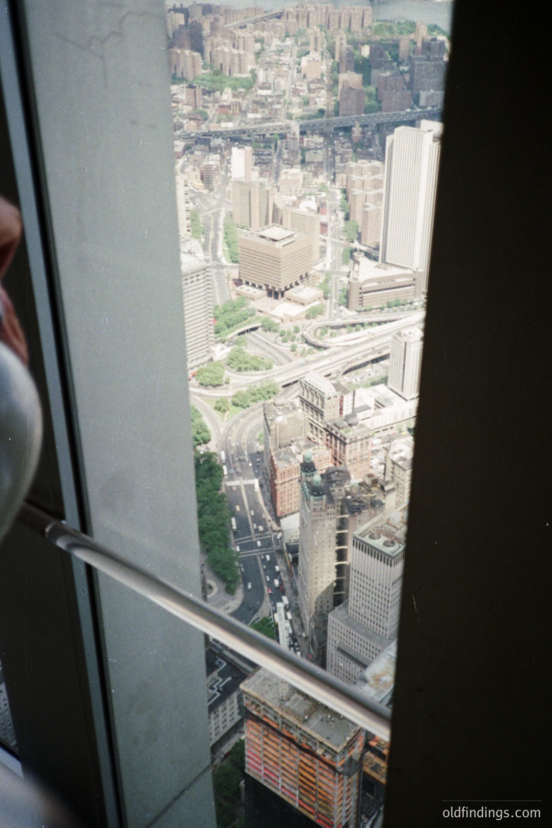 High-angle cityscape view from an elevated position, likely an observation deck or skyscraper. Dense urban architecture dominates, featuring varied building styles and a highway system. A glimpse of the Hudson River is visible in the distance. Appears to be New York City, circa 1970s-1980s. Stock photo potential for urban planning or architecture.