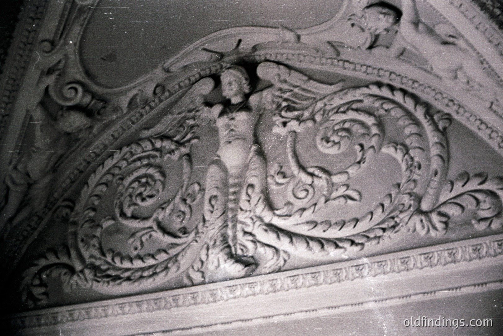 Detailed plasterwork of a female figure draped amongst scrolling foliage, likely part of a ceiling or wall relief. Classical style, ornate detailing with cherubic figures visible in the background. Appears to be from a period building, possibly 18th or early 19th century. Suitable for architectural reference.