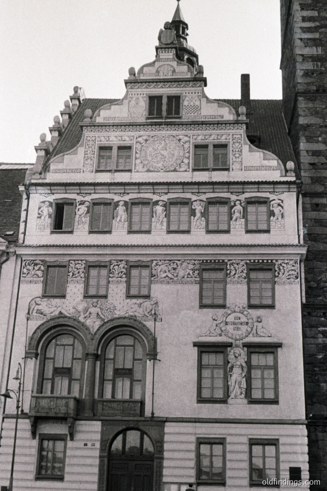 Elaborate, stucco-decorated facade of a Renaissance-era building. Features multiple windows, a balcony, and intricate sculptural reliefs depicting figures and floral motifs. Likely 16th-17th century, German origin. Illustrates civic architecture & decorative arts. Valuable for historical research & design inspiration.