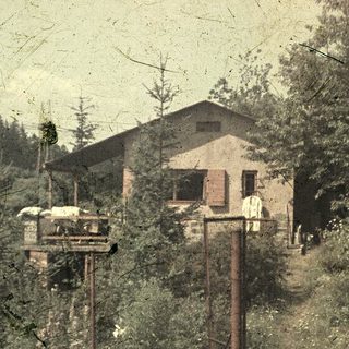 Vintage rural scene with wooden house, elevated platform, and old machinery.
