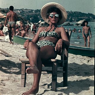 Vintage beach scene with woman in straw hat and swimsuit.