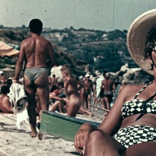 Vintage beach scene with woman in straw hat and swimsuit.
