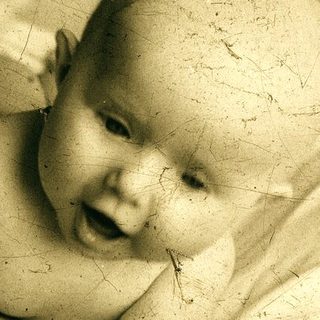 Infant lying on bed, smiling.