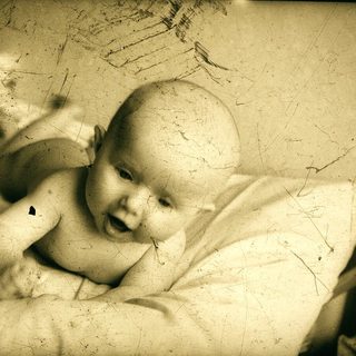 Infant lying on bed, smiling.