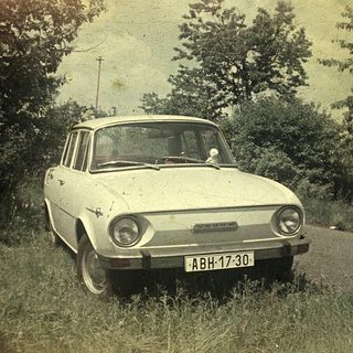 Vintage car on rural road, 1970s-era model.