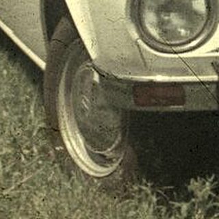 Vintage car on rural road, 1970s-era model.