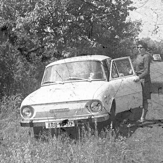 Vintage car with man posing beside it.