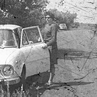 Vintage car with man posing beside it.