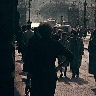 Vintage street scene with flags, historic architecture, pedestrians.