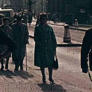 Vintage street scene with flags, historic architecture, pedestrians.