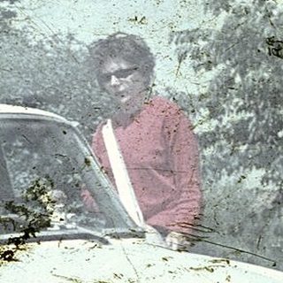 Vintage car stuck in mud with person standing nearby.